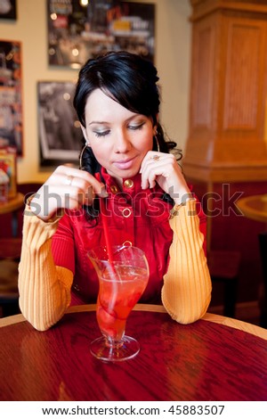 Young pretty girl is drinking cocktail and waiting for somebody in fast food restaurant