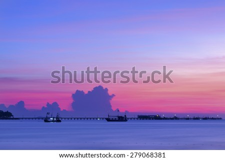The sun sets behind a little jetty , sunset beach