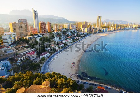 View of the sea coast with people bathing in the blue sea, on a background of city at sunset (Spain, Benidorm - Fish Eye Lens)