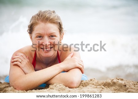 Smiling girl on the beach to sunbathe on the background of the surf (happiness on holiday)