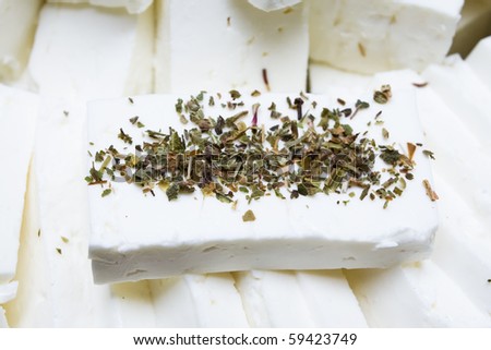 piece of cheese with fresh herbs, compared to other pieces of white cheese