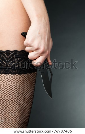 stock photo A woman with a knife in erotic stockings violence background