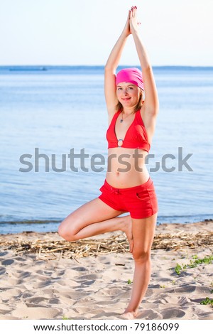 Beautiful model in a red bathing suit and bandana on a sunny beach deals yoga