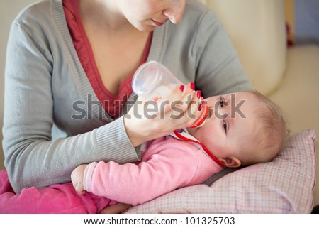 Mother feeding infant girl with a milk bottle