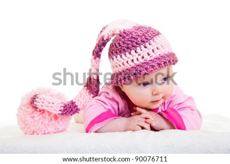 Infant baby girl raising head in funny hat isolated on white