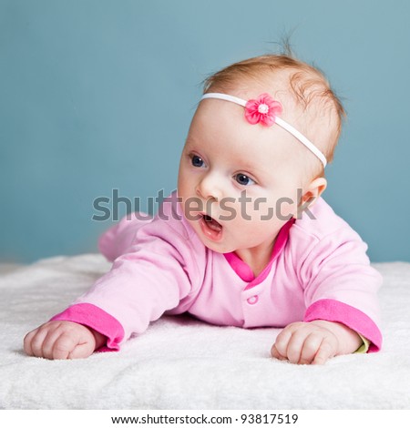 Infant baby girl raising head in funny