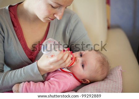 Mother feeding infant girl with a milk bottle