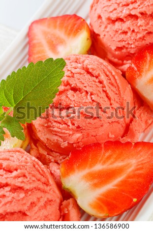 Three scoops of strawberry ice cream with fresh fruits on a tray