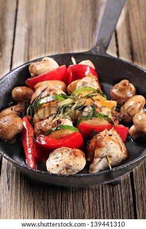 Chicken shish kebab and mushrooms in a skillet