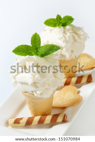 White yogurt ice cream in two waffle cones on a porcelain tray