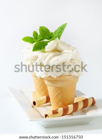 White yogurt ice cream in two waffle cones on a porcelain tray