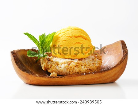 Almond cookie and scoop of ice cream served on olive wood bowl