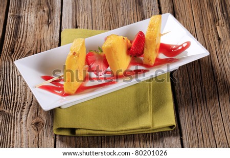 Pineapple and strawberry skewer garnished with sweet sauce