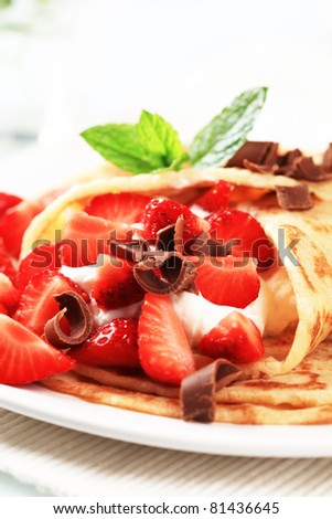 Crepes with sweet cheese and strawberries sprinkled with chocolate curls