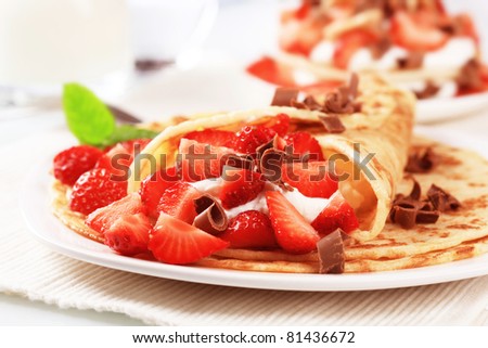 Crepes with sweet cheese and strawberries sprinkled with chocolate curls