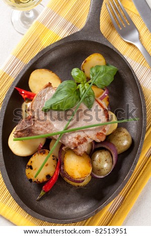 Roasted pork chop and potatoes on cast iron skillet