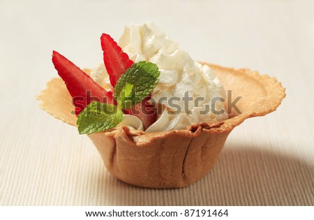 Whipped cream with strawberry in a wafer cup