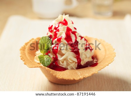 Whipped cream with strawberry sauce in a wafer cup