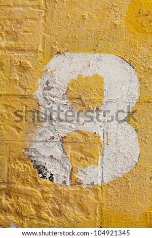 The number eight painted on a  yellow painted wall