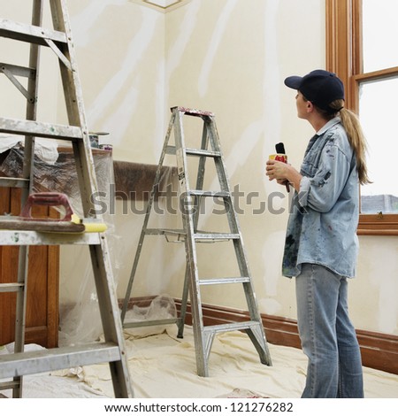 Home renovating, woman mid-thirties having a cup of tea during room painting