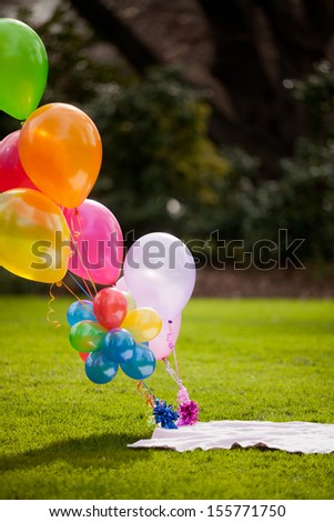 Bunch of colorful balloons filled with Helium held down with a weight