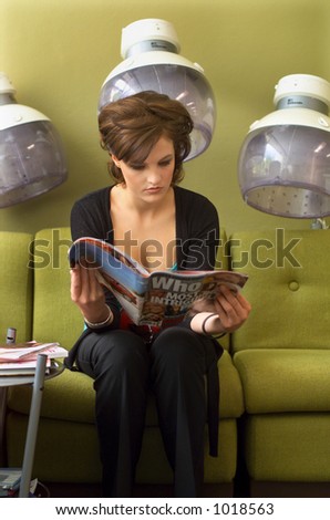 Young woman reads a magazine while waiting in a hairdressing salon