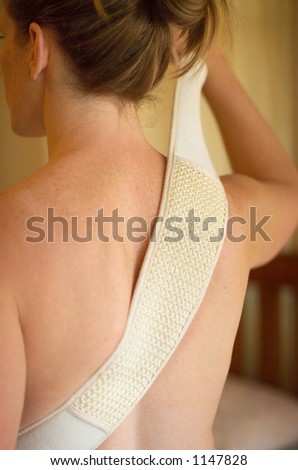Female using body exfoliating scrub on her back