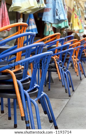 Stacks of  colourful chairs on the footpath outside CafÃ©