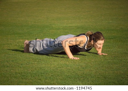 Female exercising in the park, doing Push Ups, at the low point of the exercise