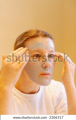 Female  looking into mirror and applying Clay Face Mask