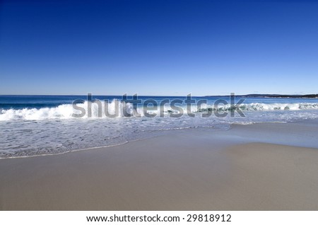 Clear blue water and smooth clean sand on an untouched pristine beach