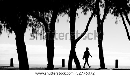 Silhouette of person walking along path in the morning near the beach