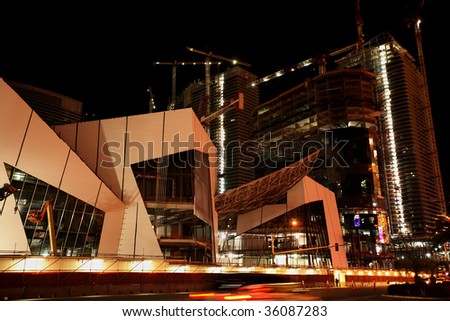 View of new commercial buildings under construction with large cranes at night