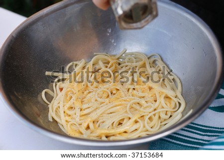 Chef adding pepper to a bowl of fresh cooked pasta