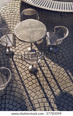 Aluminum outdoor furniture of tables and chairs in the early morning with long shadows