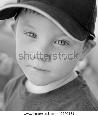 Black and White portrait of very cute four year old boy with blue eyes wearing a black baseball cap