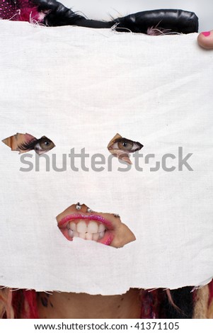 Young woman holding a face mask cut out  of material mask in front of her face