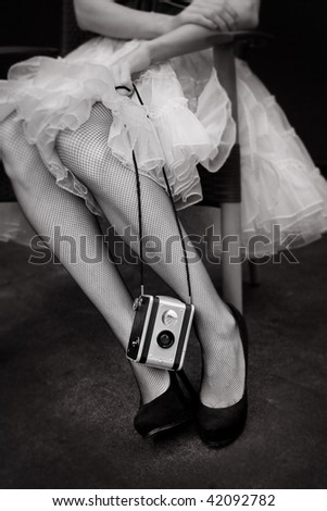 Black and White image of old style Camera and woman wearing Fishnet Stockings