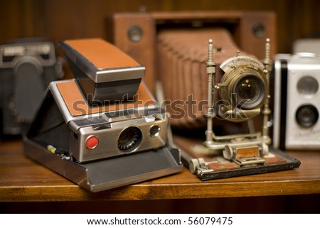 Several Antique Cameras on timber display shelf, including large format wooden camera. Deliberate shallow depth of field.