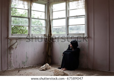 Woman  dressed in black sitting alone in an abandoned home