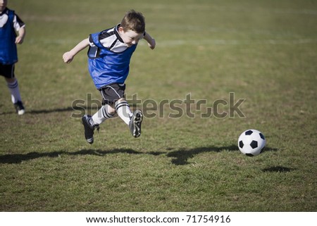 Young boy kicking soccer ball during Soccer match