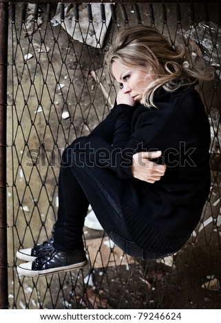 Aerial perspective view of woman curled up in fetal position on a steel and wire framed bed