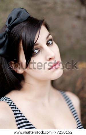 Portrait of a beautiful young woman with long brunette hair with a black bow in her hair