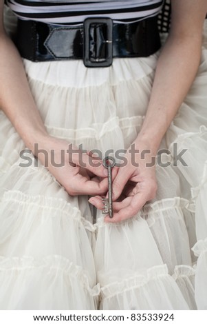 Female hands holding old door key in her hands on lap