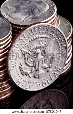 A US Kennedy Half dollar coin leaning against a stack of Washington Head Quarter Dollars