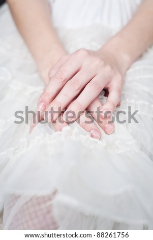 A beautiful young woman wearing a lace skirt sits with her  hands on lap