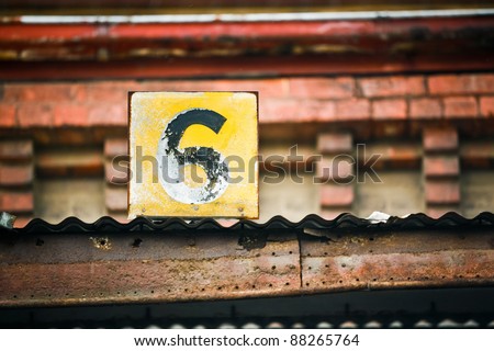 A small number six sign attached to a brick building