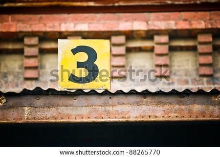A small number three sign attached to a brick building
