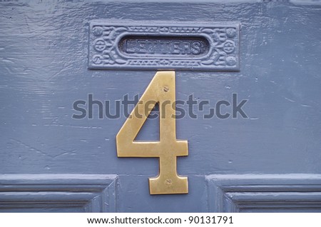 The number four in brass attached to a house front door