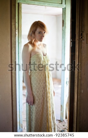 Beautiful redhead woman wearing long flowing dress standing in derelict abandoned house
